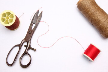 Multi-colored threads and old scissors spread out on a white floor, retro scissors, flat lay, copy space.