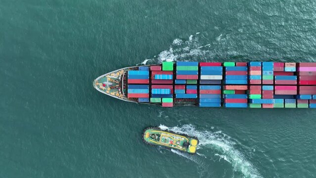 Top of cargo container ship carrying container running with tug boat for export import from cargo yard port to custom ocean concept freight shipping by ship. Tug boat drage cargo vessel to sea port