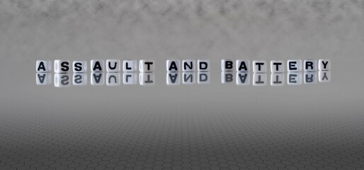 assault and battery word or concept represented by black and white letter cubes on a grey horizon...