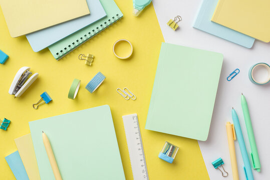 Back to school concept. Top view photo of colorful diaries sharpener ruler pens binder clips adhesive tape and mini stapler on bicolor yellow and white background