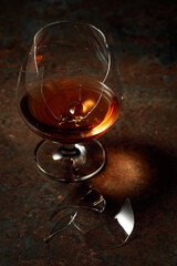 The drop of brandy falls into a broken glass.