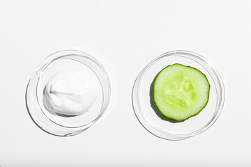 A sample of white cream, body lotion with a piece of green fresh cucumber on a white background...