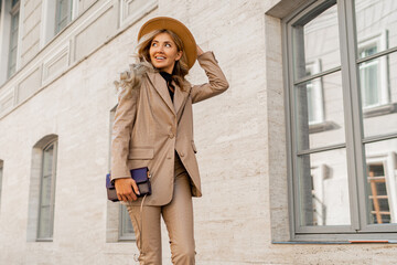 Fashion photo of gorgeous beutiful blond model posing in trendy leather  jacket and pants outdoor. Wearing beige hat.