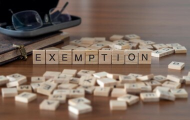 exemption word or concept represented by wooden letter tiles on a wooden table with glasses and a book - obrazy, fototapety, plakaty