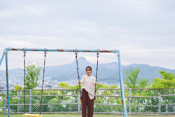 Fototapeta premium 公園でブランコをする女性