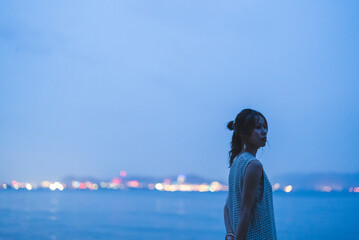 Fototapeta premium 夕暮れの海を散策する女性