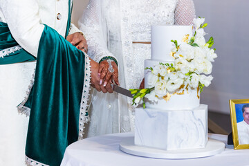 Indian married couple's cutting a wedding cake close up