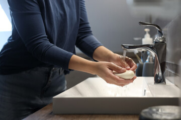 Fototapeta na wymiar Woman with soap bar washing hands in bathroom, closeup