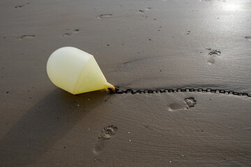 White buoy on a chain with reflection on a beach at low tide in Blankenberge, Belgium. High quality photo