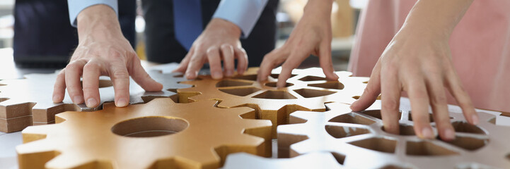 Business people making whole picture of wooden gears on workplace together in office