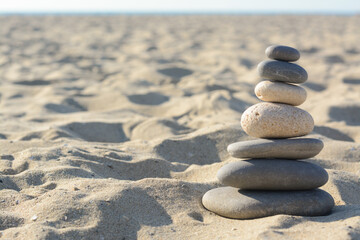 Fototapeta na wymiar Stack of stones on sandy beach, space for text