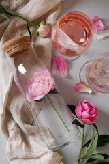Flat lay composition with rose wine and beautiful pink peonies on white background