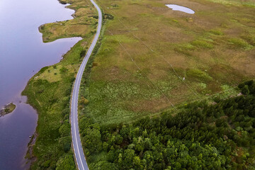 Aerial view on a lake and a small road. Vast empty green fields. Connemara, county Galway, Ireland....