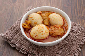 Sambal Goreng Telur Krecek, is javanese traditional food. Served in white bowl on wooden table. Seasoned with chilies and spices, spicy and delicious. A popular meal during Eid al-Fitri

