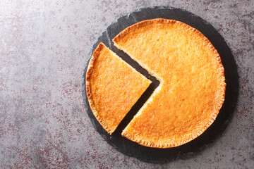 Homemade delicious dessert buttermilk pie in a slate plate on the table. Horizontal top view from above - obrazy, fototapety, plakaty