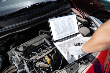 Mechanic With Laptop While Examining Engine