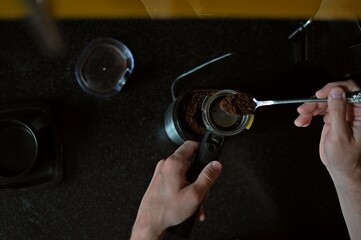 Americano brew. A man pours coffee into a coffee machine. Ground coffee. Shooting from above.