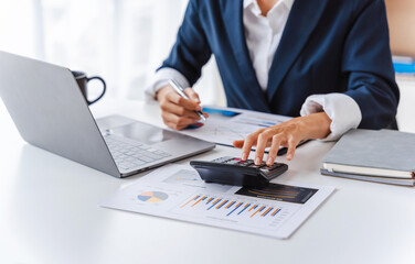 Close up accountant business woman using laptop at workplace with financial reports.