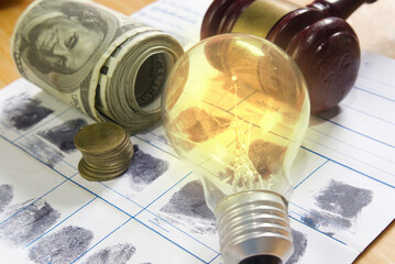 Energy law concept.Bulb Light and banknote on fingerprint crime page file.