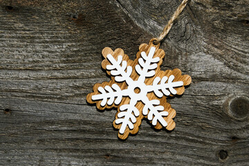 Christmas decoration in the form of a snowflake on a wooden background. Top view, place for text.