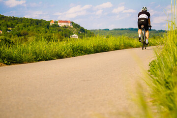 Młoda osoba jadąca na rowerze w piękny letni dzień w weekend - obrazy, fototapety, plakaty