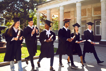 Diverse group of students after outdoor graduation ceremony. Happy multiethnic graduates in caps...