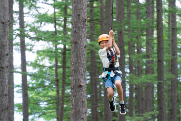 夏休みにジップラインで遊ぶアジア人の小学生