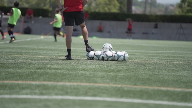 Soccer coach looking out at youth players dribbling ball