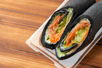 Black tortilla wrap with salted salmon and vegetables