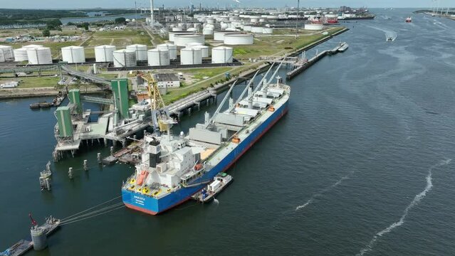 Bulk Carrier Ship at Port Offloading Cargo and Commodities by Shore Crane