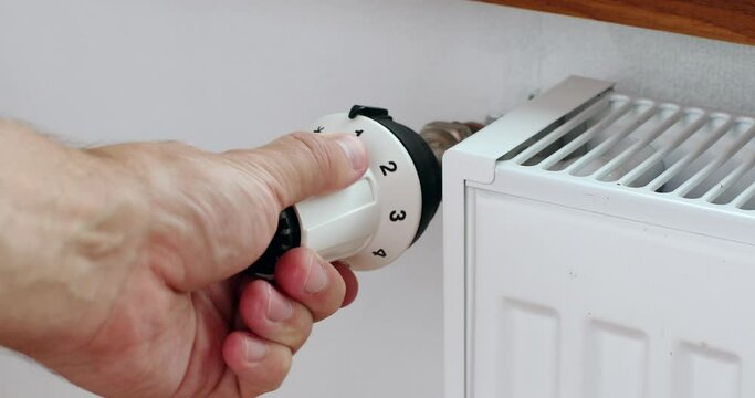 Man hand changing the temperature on the radiator by temperature controller