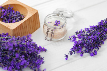 Lavender bath salt and dried flowers of lavender on white wooden background