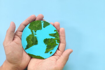 Top view of human hand holding planet earth model with green leaves. World earth day, save the environment, environmental conservation, protection, esg and csr concept.