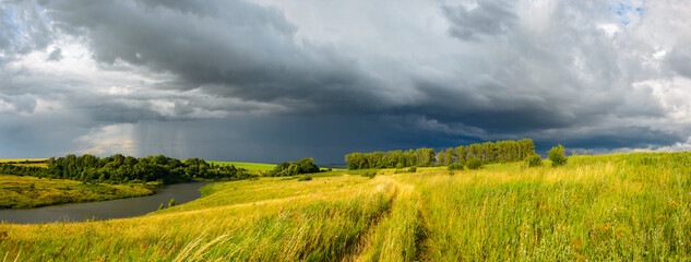 Summer rual scene with dark stormy clouds over the farm fields
