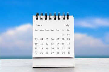 July 2023 desk calendar for planners and reminders on a black table on the sky background.