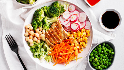 Chicken buddha bowl with meat, colorful vegetables on base of brown rice.