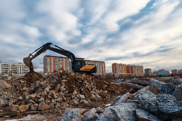 Obraz premium Excavator pours soil on pile of garbage at demolition site