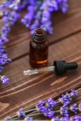 Herbal lavender oil bottle with flowers on wooden background