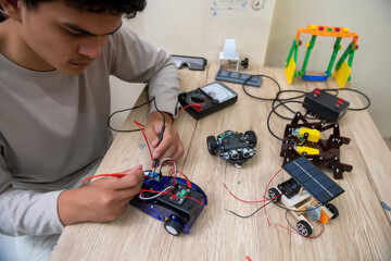 Asian teen plugs power and signal cables into toy car workshop sensor chip Make an Arduino Robot Project at Home
