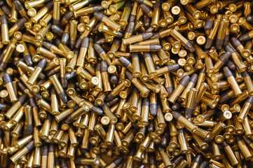 Heap of black and golden small-caliber bullets on table