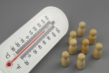 Overheating affects people health concept. Thermometer and wooden people figures on gray background.	