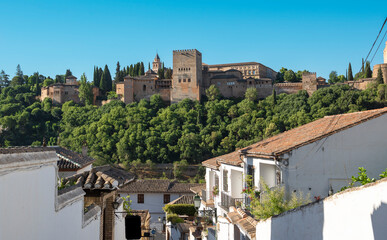 Una calle con las tradicionales casas blancas del sur de España con la Alhambra al fondo en la...