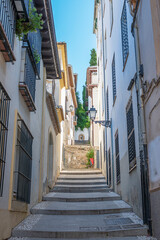 Una callejuela estrecha escalonada y en cuesta con casas blancas tradicionales del sur de España en el barrio antiguo de la ciudad de Granada