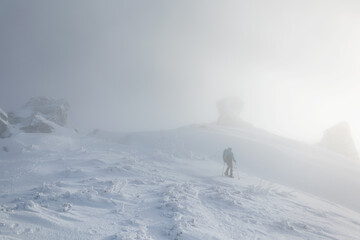 Fototapeta na wymiar A woman in the winter trekking during the fog