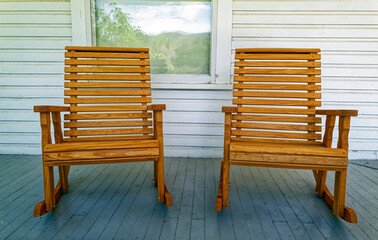 Two wood rocking chairs set on a white wood porch