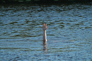 a man's hand above the surface of the water in the river, saving drowning