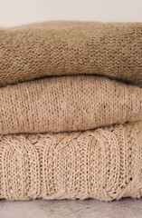 Fototapeta na wymiar closeup knitted textures of beige wool sweaters. stack of cozy autumn and winter knitwear