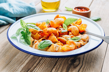 Pasta with mushrooms tomato sauce and basil on wooden background.