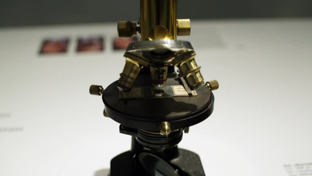 Pan down to an ancient microscope model made from brass, being displayed in an optics museum