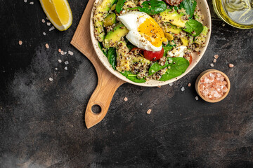 Quinoa buddha bowl with avocado, egg, tomatoes, spinach and sunflower seeds on a dark background. Homemade food. Healthy, clean eating. Vegan or gluten free diet, place for text, top view